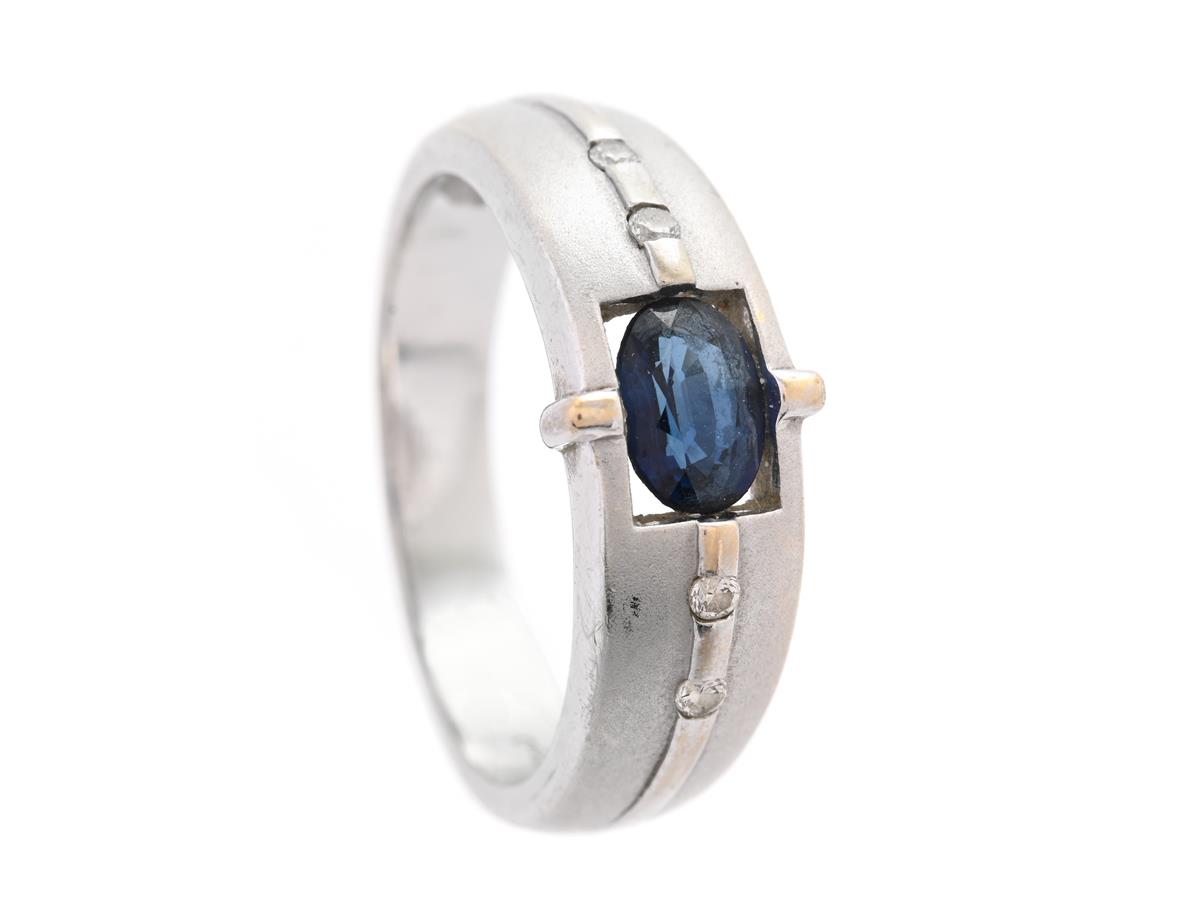 RING, 18K vitguld, delvis mattera yta, ovalslipad blå safir ca 0,57 ct, 4 briljantslipade diamanter ca 0,05 ctv, stl 17 mm, vikt 4,9 g.