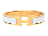 HERMÈS, ARMRING, Clic Clac H Bracelet, vit emalj, guldfärgade beslag, bredd 1 cm, diameter 5,5 cm, smyckespåse på auktion i Stockholm, Stockholms län hos Kaplans Auktioner
