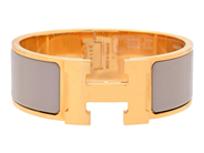 HERMÈS, ARMRING, Clic Clac H Bracelet, beige emalj, guldfärgade beslag, bredd 2 cm, diameter 5 cm, originalkvi på auktion i Stockholm, Stockholms län hos Kaplans Auktioner