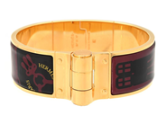 HERMÈS, ARMRING, Charniere Bracelet, svart, vinröd emalj, guldfärgat spänne, diameter ca 6 cm, bredd 2 cm, Mad på auktion i Stockholm, Stockholms län hos Kaplans Auktioner