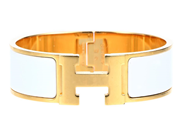 HERMÈS, ARMRING, Clic Clac H Bracelet, vit emalj, guldfärgade beslag, bredd 2 cm, diameter 5,5 cm, repor. Good på auktion i Stockholm, Stockholms län hos Kaplans Auktioner